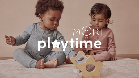 Two kids in baby sleepsuits playing with MORI's Wooden Star Shape Sorter